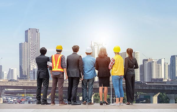 Team of professionals in suits and construction clothes staring at a city skyline