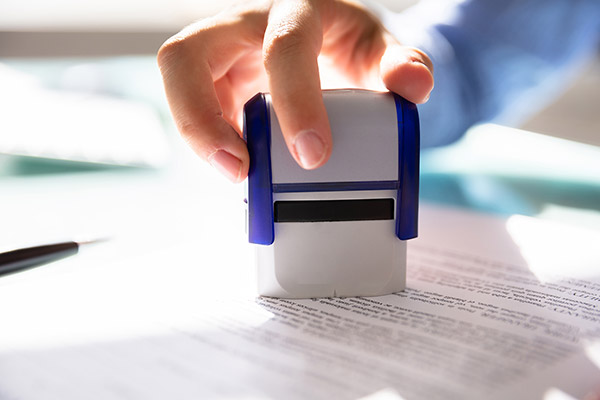 Close up of a hand stamping a word document with a self-inking stamp.