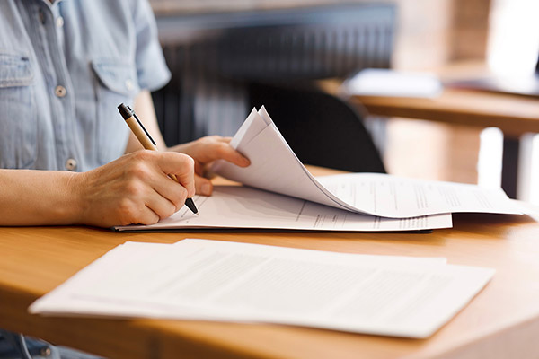 Applicant filling out California commercial bond application form with a pen in a bright workspace