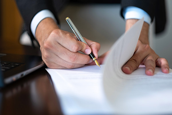 Business professional signing paperwork with fountain pen