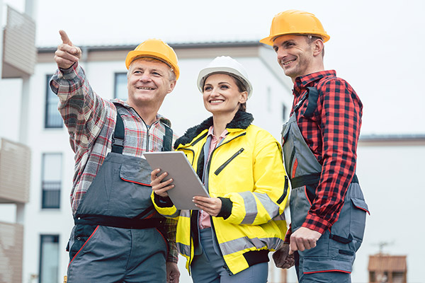A contractor points ahead to show a builder and another contractor something in front of them.